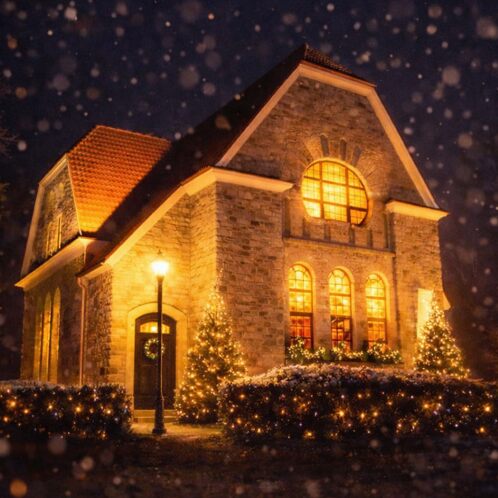 Festlich beleuchtete Neanderkirche in Hochdahl bei Nacht, mit warmem Licht an Fassade und Turm vor dunklem Himmel.